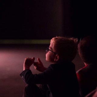 "Pan Dźwięk" - spektakl i warsztaty - Chłopczyk w okularach siedzi na podłodze. Zamyślony, wpatruje się w przestrzeń.