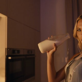 The end - Kadr z filmu. Kobieta polewa się mlekiem ze szklanej butelki.