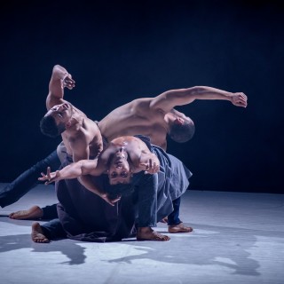 "Zatańczone" - wystawa. 10 lat festiwalu Scena Otwarta - Scena ze spektaklu. Trzech mężczyzn w pozie tanecznej. Leżą na podłodze, blisko siebie.