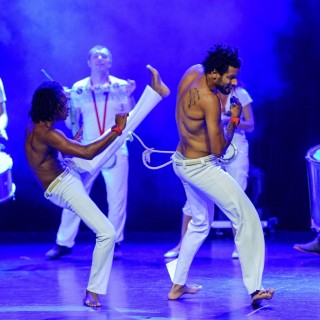 Muzyczne Tarasy - Fiesta Brazylijska - Meżczyżni w baiłych ubraniach. Na pierwszym planie pokaz caopeiry.