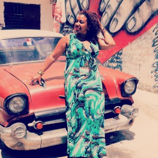 Muzyczne Tarasy - One Night in Havana Salsa Latina - Kobieta w zielonej sukience opiera się o maskę czerwonego samochodu.