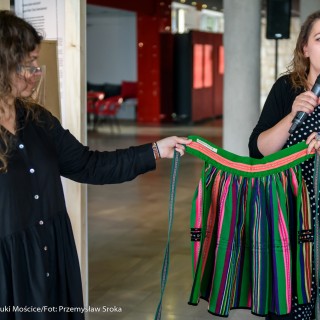 Nastrój się na strój! Tradycja na podszewce - oprowadzanie kuratorskie - Dwie kobiety trzymają kolorową spódnice, jedna a nich mówi coś do mikrofonu.  - Fot : Przemysław Sroka