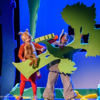"Wystarczy być" - spektakl dla dzieci Teatru Maska - Mężczyzna i kobieta w przebraniach trzymają sztuczne drzewo. - Fot : Przemysław Sroka
