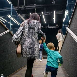 "Wystarczy być" - spektakl dla dzieci Teatru Maska - Kobieta w płaszczu wchodzi po schodach trzymając za rękę dziecko. - Fot : Przemysław Sroka