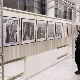 Spotkanie z biografem Leopolda Tyrmanda, Marcelem Woźniakiem - Kobieta w maseczce przygląda się zdjęciom na wystawie.