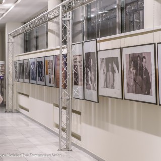 Spotkanie z biografem Leopolda Tyrmanda, Marcelem Woźniakiem - Kobieta w płaszczu i w maseczce ogląda zdjęcia na wystawie.