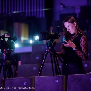 Koncert Patriotyczny Kwartetu Smyczkowego Filharmonii Krakowskiej - Kobieta na widowni nagrywa występ za pomocą dwóch kamer.