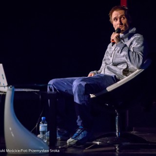 Festiwal Górnolotni 2021. Dzień pierwszy. - Mężczyzna siedzi i mówi do mikrofonu patrząc w bok.  - Fot : Przemysław Sroka