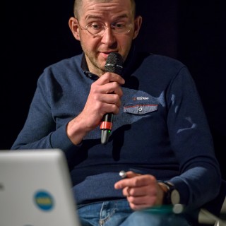 Festiwal Górnolotni 2021. Dzień drugi. - Mężczyzna w okularach mówi do mikrofonu i patrzy na laptopa. - Fot : Przemysław Sroka