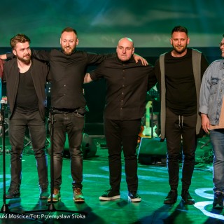 "Znów wędrujemy" - widowisko muzyczne - Mężczyzna w okularach, czterech mężczyzn w czarnych ubraniach oraz mężczyzna w żakiecie stoją w rzędzie na scenie.  - Fot. : Przemysław Sroka