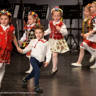 "Matulu, wyjrzyj na próg chaty" - występ Małych Świerczkowiaków - Dziewczynki w kolorowych strojach ludowych z wiankami na głowach tańczą na scenie w parach, jedna dziewczynka tańczy z chłopczykiem w białej bluzce i czerwonej kokardce. - Fot. : Przemysław Sroka