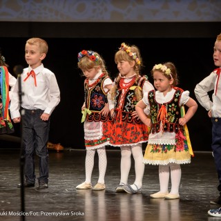 "Matulu, wyjrzyj na próg chaty" - występ Małych Świerczkowiaków - Dziewczynki w kolorowych strojach ludowych z wiankami na głowach i chłopcy w białych koszulach z czerwonymi kokardkami stoją w rzędzie na scenie z rękami położonymi na biodrach. - Fot. : Przemysław Sroka