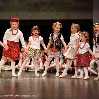 "Matulu, wyjrzyj na próg chaty" - występ Małych Świerczkowiaków - Dziewczynki w kolorowych strojach ludowych z wiankami na głowach stoją na scenie, trzymając się za ręce, reszta siedzi za nimi na podłodze. - Fot. : Przemysław Sroka