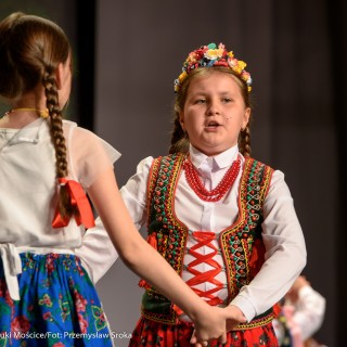 "Matulu, wyjrzyj na próg chaty" - występ Małych Świerczkowiaków - Dwie dziewczynki w kolorowych strojach ludowych tańczą trzymając się za ręce, jedna z nich ma wianek na głowie, druga wstążki w warkoczach. - Fot. : Przemysław Sroka
