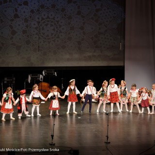 "Matulu, wyjrzyj na próg chaty" - występ Małych Świerczkowiaków - Dziewczynki w kolorowych strojach ludowych z chłopcami w białych koszulach i czerwonych kokardkach stoją na scenie w połkole, trzymając się za ręce. - Fot. : Przemysław Sroka