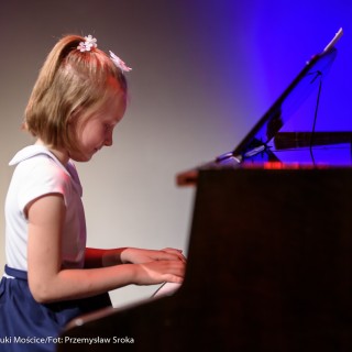 MiniLab - zakończenie roku 2020/2021 - Dziewczynka w białej bluzce i granatowej spódnicy gra na fortepianie.  - Fot. :Przemysław Sroka