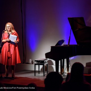 MiniLab - zakończenie roku 2020/2021 - Kobieta w czerwonej sukience mówi do mikrofonu, trzymając w ręce podkładkę. - Fot. :Przemysław Sroka