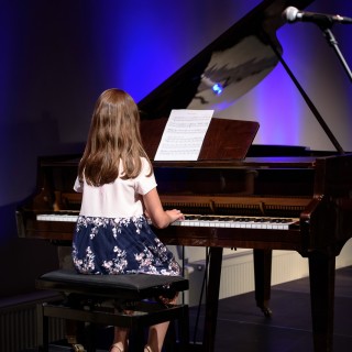 MiniLab - zakończenie roku 2020/2021 - Dziewczynka w biało-niebieskiej sukience gra na fortepianie.  - Fot. :Przemysław Sroka