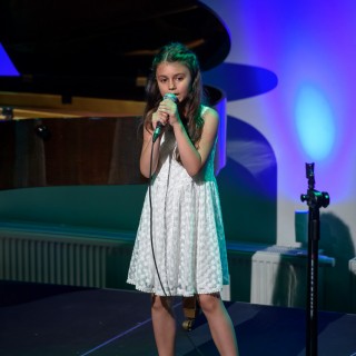 MiniLab - zakończenie roku 2020/2021 - Dziewczynka w białej sukience śpiewa do mikrofonu na scenie.  - Fot. :Przemysław Sroka