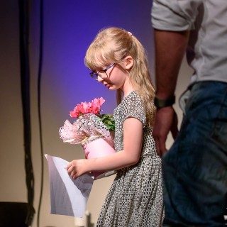 MiniLab - zakończenie roku 2020/2021 - Dziewczynka w okularach i sukience w jednej ręce trzyma kwiaty w doniczce, a w drugiej kartkę z nutami.  - Fot. :Przemysław Sroka