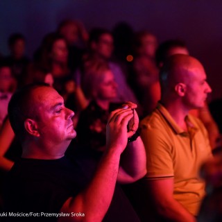 MiniLab - zakończenie roku 2020/2021 - Ludzie na widowni oglądają występ, mężczyzna robi zdjęcia telefonem.  - Fot. :Przemysław Sroka