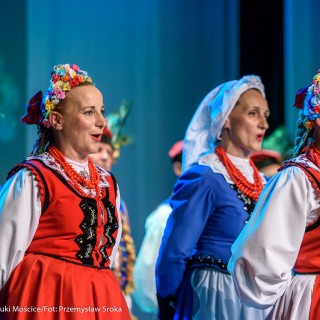 Świerczkowiacy - zakończenie sezonu artystycznego 2020/2021 - Kobiety w czerwonych i niebieskich sukniach ludowych z wiankami lub chustami na głowach śpiewają na scenie. - Fot. :Przemysław Sroka