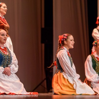 Świerczkowiacy - zakończenie sezonu artystycznego 2020/2021 - Kobiety w strojach ludowych z kwiatami wpiętymi we włosy śpiewają, trzy z nich siedzą na scenie, dwie stoją za nimi. - Fot. :Przemysław Sroka