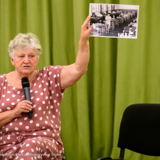 Czym są dla Was Mościce? - spotkanie - Kobieta mówi do mikrofonu trzymając w dłoni czarno-białe zdjęcie. - Fot.: Przemysław Sroka