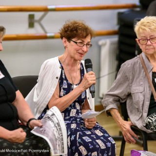 Czym są dla Was Mościce? - spotkanie - Trzy kobiety siedzą obok siebie. Kobieta w środku mówi do mikrofonu. - Fot.: Przemysław Sroka