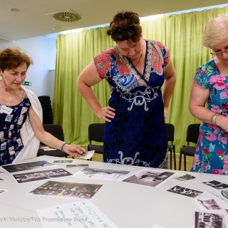 Czym są dla Was Mościce? - spotkanie - Grupa kobiet pochyla się nad stołem, na którym rozłożone są zdjęcia. - Fot.: Przemysław Sroka