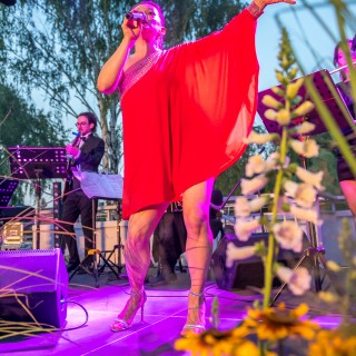San Luis Tango i Magdalena Lechowska - Muzyczne Tarasy 2021 - Wokalistka w czerwonej sukience śpiewa do mikrofonu unosząc jedną rękę. Za nią mężczyzna gra na gitarze. - Fot.: Przemysław Sroka