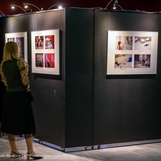 "Bożyszcze kobiet" - spektakl Teatru Capitol - Kobieta w czarnej sukience ogląda zdjęcia na wystawie. - Fot.: Przemysław Sroka
