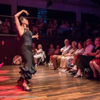 Gang Tango i Lala Czaplicka - Muzyczne Tarasy 2021 - Kobieta w czarnej sukience tańczy na scenie. Ludzie siedzą na widowni i ogladają występ.  - Fot.: Przemysław Sroka