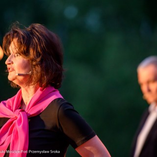 "Małe zbrodnie małżeńskie" - Muzyczne Tarasy 2021 - Kobieta w czarnej bluzce i różowej chustce mówi do mikrofonu, za nią w tle mężczyzna w marynarce. - Fot.: Przemysław Sroka