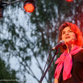 "Małe zbrodnie małżeńskie" - Muzyczne Tarasy 2021 - Kobieta w czarnej bluzce i różowej chustce śpiewa do mikrofonu. - Fot.: Przemysław Sroka