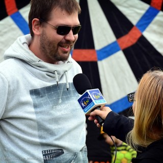 Festiwal Tarnowianie - dzień 2 - Mężczyzna w okularach przeciwsłonecznych, mówi do mikrofonu, który trzyma kobieta.  - Fot. Przemysław Sroka i Michał Żurowski