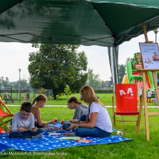 Festiwal Tarnowianie - dzień 2 - Kobieta i trójka dzieci siedzą na kocu rozłożonym na trawie pod baldachimem i jedzą owoce. - Fot. Przemysław Sroka i Michał Żurowski