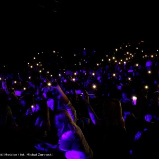 Koncert Kwiatu Jabłoni - Widownia trzyma w górze telefony z zaświeconymi latarkami. W ciemności migają setki światełek. - fot. Michał Żurowski