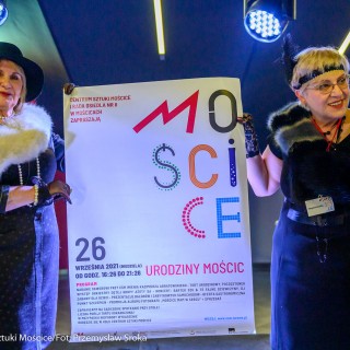 Urodziny Mościc - Dwie kobiety w eleganckich sukniach trzymają plakat z podpisem "Urodziny Mościc". - Fot. Przemysław Sroka i Michał Żurowski