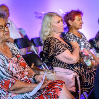 Senior w Centrum - Narodowe Czytanie - "Nad Niemnem" - Trzy kobiety siedzą na widowni i słuchają Anny Krakowskiej. Dwie z nich się uśmiechają. - Fot: Przemysław Sroka
