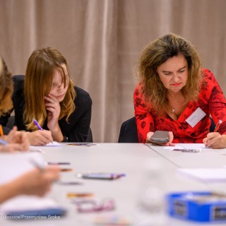 Warsztaty poetyckie Źródło - Kobiety siedzą przy stole i piszą na kartkach. - Fot: Przemysław Sroka