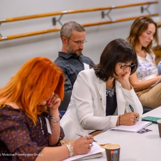 Warsztaty poetyckie Źródło - Trzy kobiety i mężczyzna siedzą przy stole. Kobiety ze skupieniem piszą na kartkach. - Fot: Przemysław Sroka