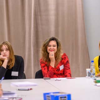 Warsztaty poetyckie Źródło - Uczestniczki warsztatów siedzą przy stole. Jedna z kobiet uśmiecha się. - Fot: Przemysław Sroka