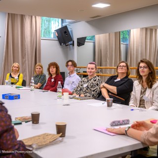 Warsztaty poetyckie Źródło - Uczestnicy warsztatów siedzą obok siebie dookoła stołu. Kilka osób się uśmiecha. - Fot: Przemysław Sroka