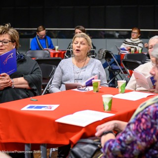 Senior w Centrum - Kolędowanie - Kobiety siedzą przy stole i śpiewają. - Fot: Przemysław Sroka