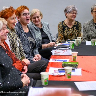 Senior w Centrum - Kolędowanie - Kobiety siedzą przy stole i śpiewają. - Fot: Przemysław Sroka