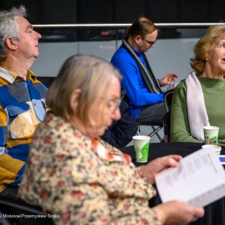 Senior w Centrum - Kolędowanie - Uczestnicy wydarzenia siedzą przy stołach i trzymają śpiewniki w dłoniach. - Fot: Przemysław Sroka