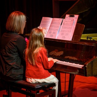 Koncert Pianistów Laboratorium Artystycznego - Dziewczynka i kobieta grają na fortepianie. - Fot: Przemysław Sroka